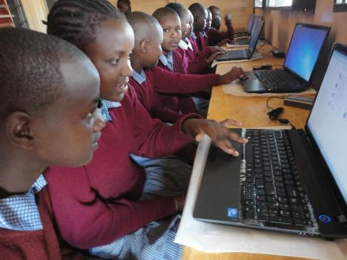Girls at Ngeya School learning on a computer.